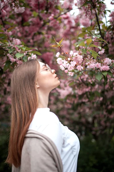Красива молода щаслива жінка в блузці і окулярах біля вишневого цвіту — стокове фото