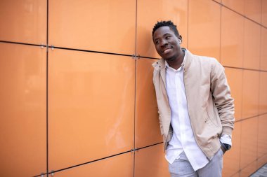 Ceketli ve beyaz gömlekli yakışıklı genç adam kulaklıkla müzik dinliyor.