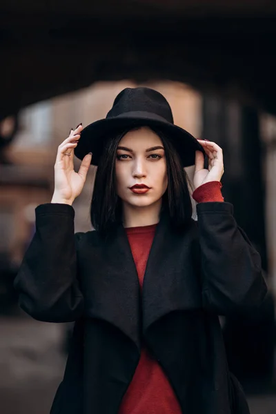 Bela jovem mulher em um casaco preto e chapéu — Fotografia de Stock