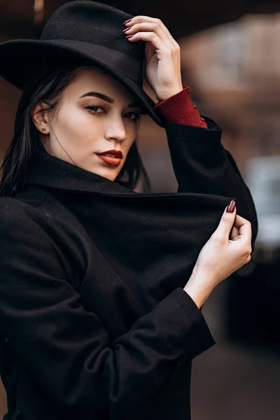 Beautiful young woman in a black coat and hat — Stock Photo, Image