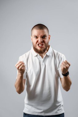 Gri bir arka planda, bağıran yakışıklı bir gencin portresi. İzole. kopyalama alanı