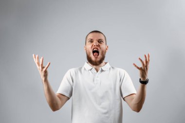 Gri bir arka planda, bağıran yakışıklı bir gencin portresi. İzole. kopyalama alanı