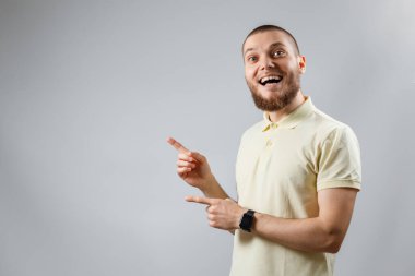 Sarı tişörtlü genç bir adamın portresi gri arka planda bir tarafı gösteriyor. İzole. kopyalama alanı