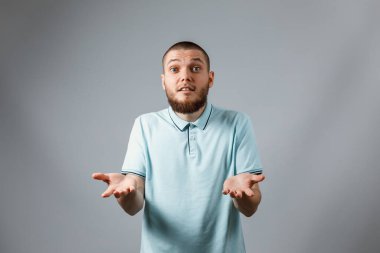 Gri arka planda kaybolmuş mavi tişörtlü genç bir adamın portresi. İzole. Para yok.