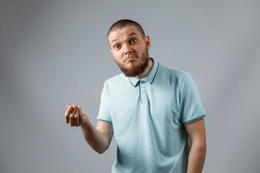 Gri arka planda kaybolmuş mavi tişörtlü genç bir adamın portresi. İzole. Para yok.