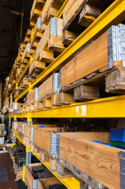 Depo depolama raf ahşap kutular ve ağır endüstriyel metal araçları ve bölümleri içeren palet ile dolu. Yandan vurdu.