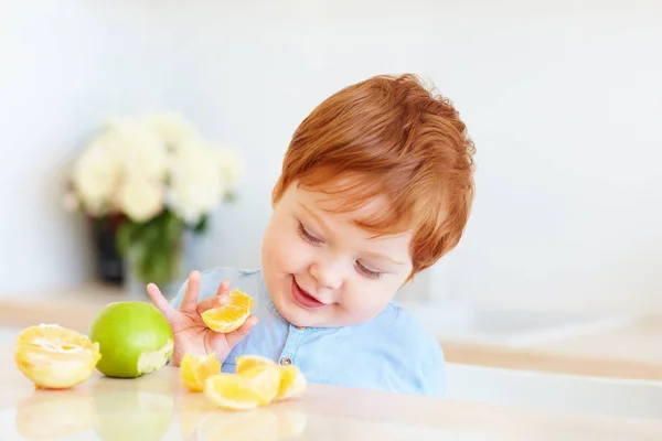 Bonito Ruiva Criança Bebê Degustação Fatias Laranja Maçãs Cozinha — Fotografia de Stock