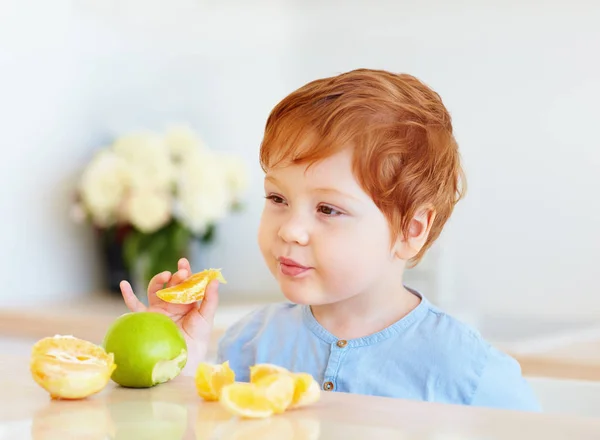 Bonito Ruiva Criança Bebê Degustação Fatias Laranja Maçãs Cozinha — Fotografia de Stock