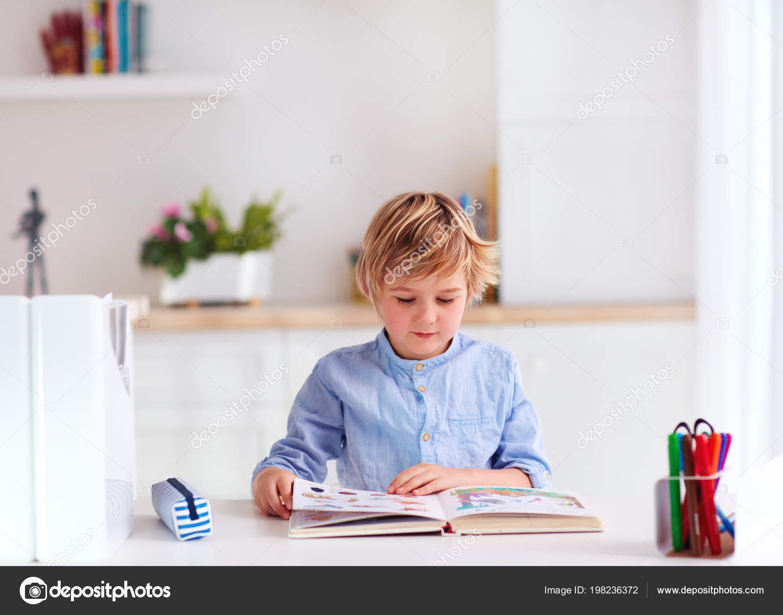 Young Kid Boy Reading Book While Sitting Desk Home Stock Photo