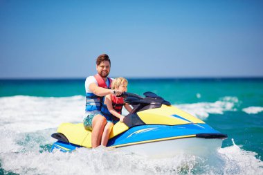 mutlu, heyecanlı bir aile, baba ve oğul eğleniyor jet ski yaz tatili