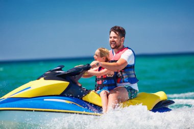 mutlu, heyecanlı bir aile, baba ve oğul eğleniyor jet ski yaz tatili