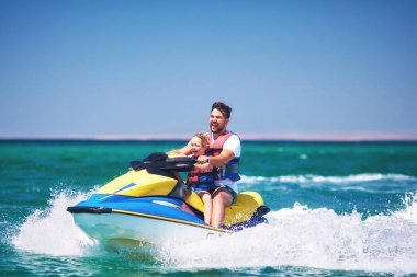 mutlu, heyecanlı bir aile, baba ve oğul eğleniyor jet ski yaz tatili