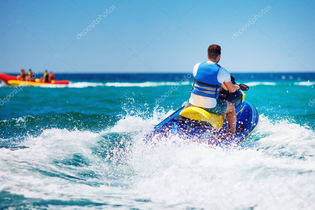 young adult man running the wave on jet ski during summer vacation