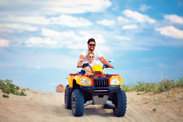 Família feliz, pai e filho montando em quadriciclo ATV na praia de areia — Fotografia de Stock