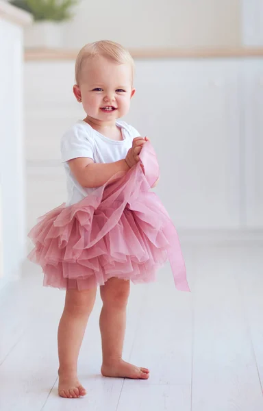 チュチュ スカートのかわいい赤ちゃん女の子が家の床の上に立つ — ストック写真