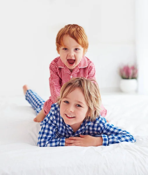 幸せな若い子供、兄弟はパジャマ姿で寝室で遊んで — ストック写真