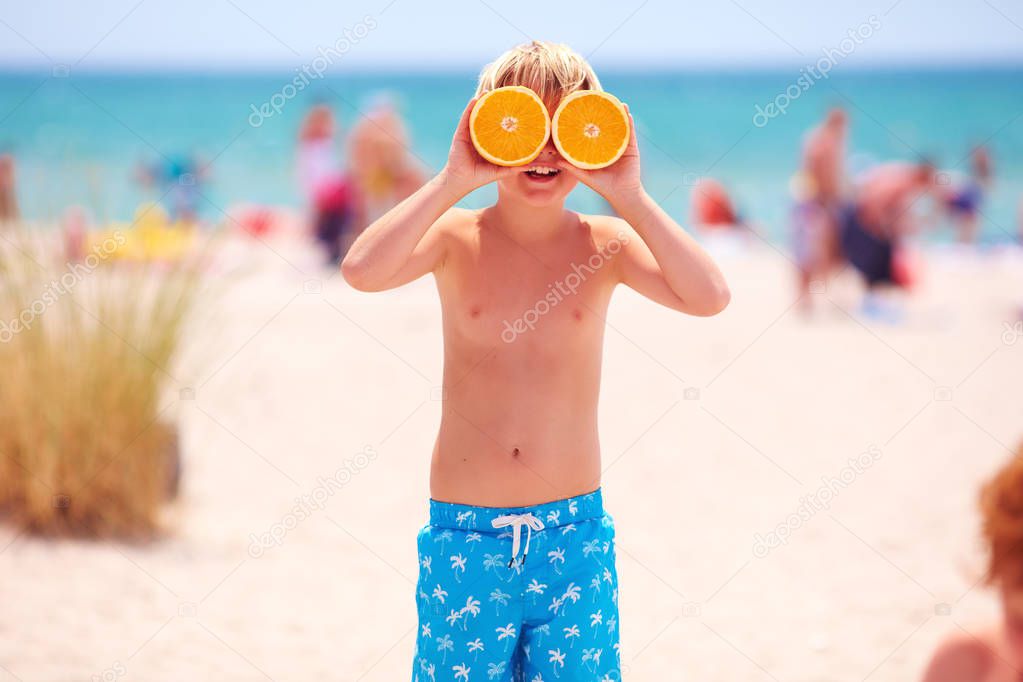 happy young boy, kid with citrus eyes on sandy beach during summer vacation