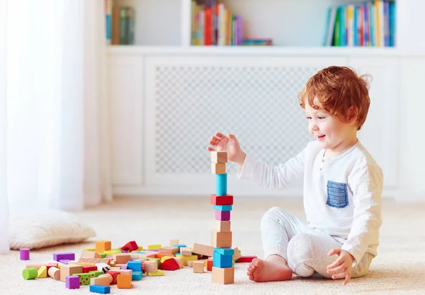 Cute toddler baby boy playing with wooden blocks, building a balancing high tower — Stock Photo, Image