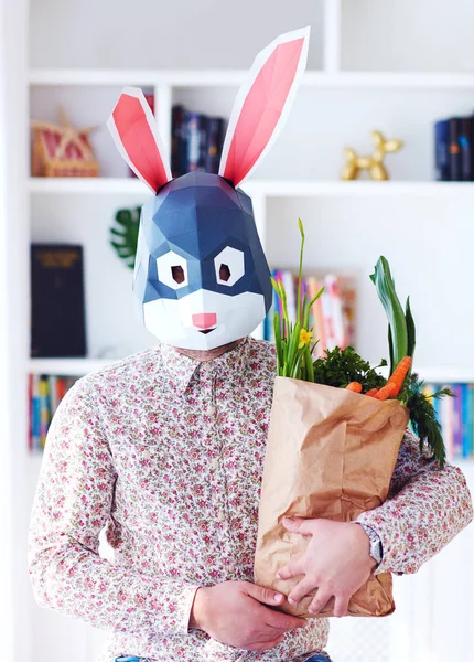 Królik młodego dorosłego królika posiadający papierową torbę pełną świeżych zieleni i marchwi — Zdjęcie stockowe
