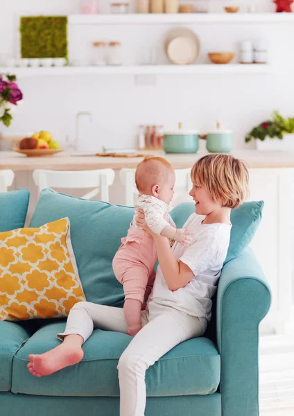 Bonito jovem menino brincando com pouco infantil bebê irmã em casa em — Fotografia de Stock