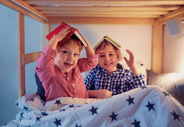 Niños alegres, hermanos divirtiéndose, jugando con libros en la litera durante la hora de acostarse —  Fotos de Stock