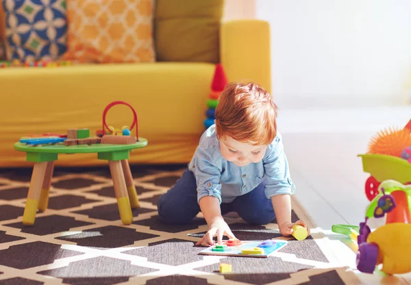 Bonito criança bebê menino brincando com brinquedos no tapete em casa — Fotografia de Stock
