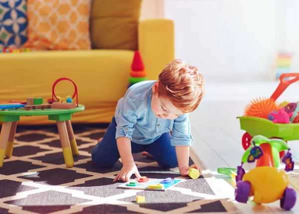 Lindo bebé niño jugando con juguetes en la alfombra en casa — Foto de Stock