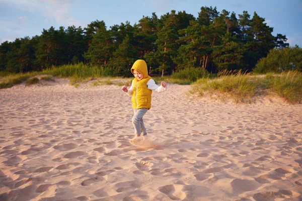 Glad pojke ha roligt, kör på sandstranden höst strandnära tallskogen — Stockfoto