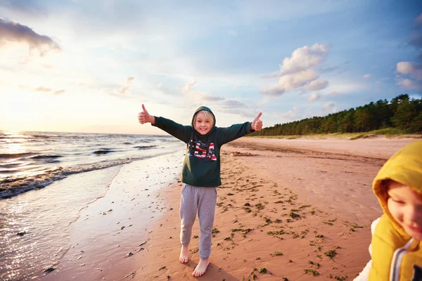 Feliz animado meninos se divertindo em uma praia de outono arenoso, com polegares para cima gesto — Fotografia de Stock