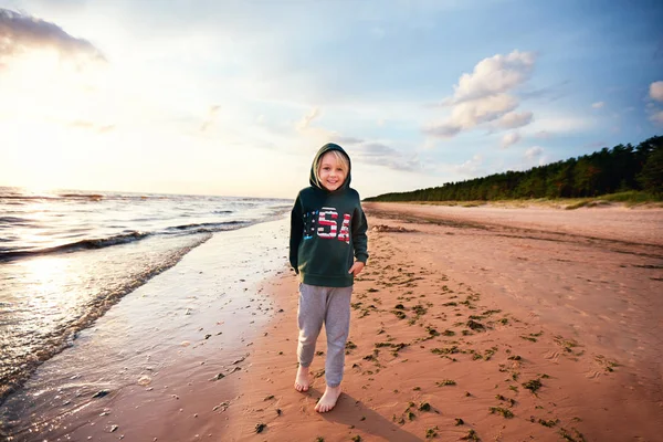 Netter kleiner Junge, der Spaß am Sandstrand in der Nähe des Kiefernwaldes hat, ehrlicher Lebensstil — Stockfoto