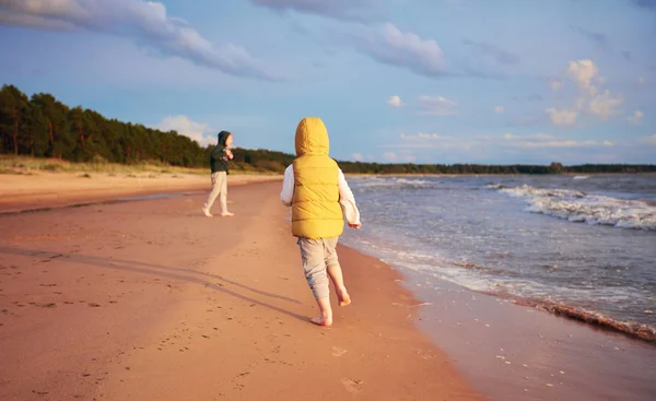 Carino giovani ragazzi, famiglia divertirsi, in esecuzione sulla spiaggia sabbiosa autunno vicino alla pineta — Foto Stock