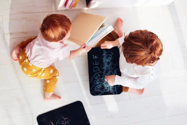 分散注意力，可爱红头发的兄弟姐妹玩乐，在地板上玩粉笔板和书本 — 图库照片
