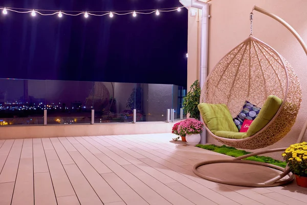 rooftop patio area with hanging swing chair and string lights at