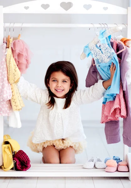 Hermosa chica joven, niño que se divierte entre la prenda, la elección de vestido de fiesta en el armario — Foto de Stock