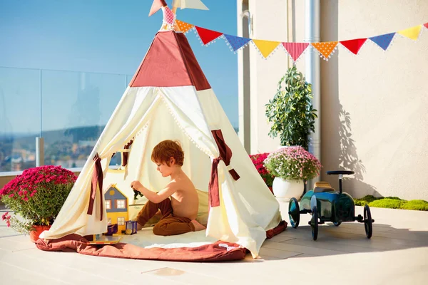 Aranyos kisgyerek, fiú játszik békésen belül egy sátor a napos tetőteraszon — Stock Fotó