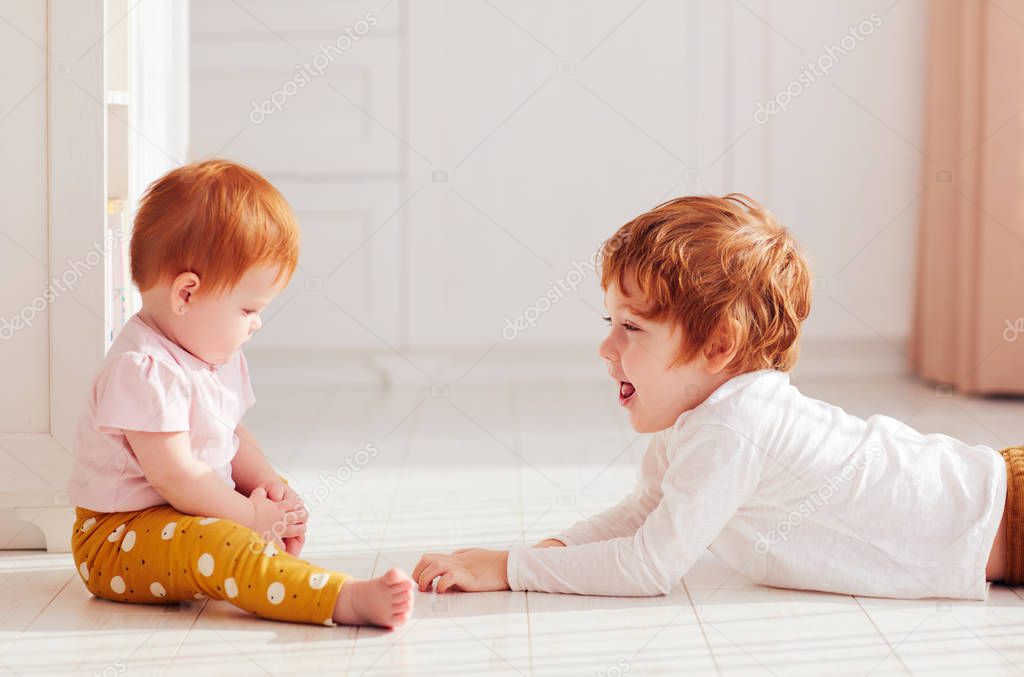 cute happy redhead siblings, brother and sister having fun together, playing at home