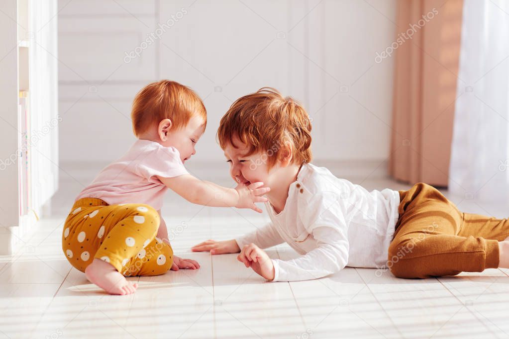 cute happy redhead siblings, brother and sister having fun together, playing at home