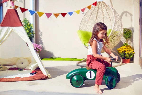 Niedliches Junges Mädchen Kind Reitet Spielzeugauto Spielt Auf Der Sommerterrasse — Stockfoto