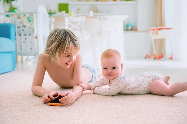 幸せな赤ちゃんの女の子遊びます兄と一緒にカーペットの上で自宅で — ストック写真