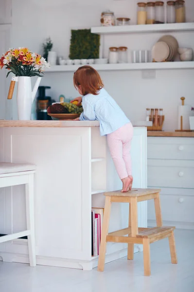 Bébé Fille Curieuse Essayant Atteindre Fruit Sur Table Dans Cuisine — Photo