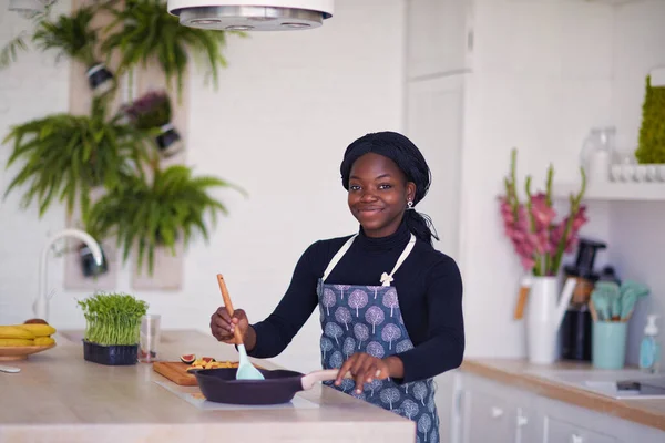 一位年轻美丽的非洲女人正在厨房里做饭 — 图库照片