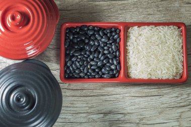 pirinç ve fasulye ham ahşap arka plan üzerinde kırmızı kap içinde.