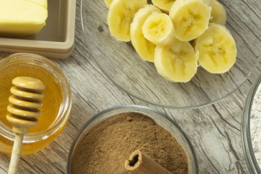 Sağlıklı bisküvi yapmak için malzemeler. Muz, yulaf'ın un, bal, tarçın ve ahşap masa üzerine tereyağı.