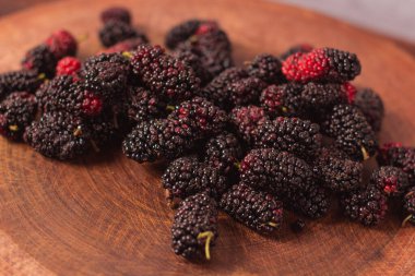 Taze böğürtlenler ahşap masada mavi bir kasede kırsal bir kenevirle