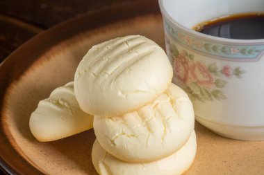 Küçük yuvarlak kurabiyeler ve kahverengi tabakta bir fincan kahve.