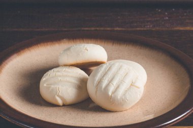 Küçük yuvarlak kurabiyeler ve kahverengi tabakta bir fincan kahve.