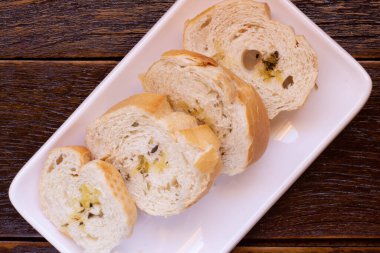 White dish with toasted bread on wooden background