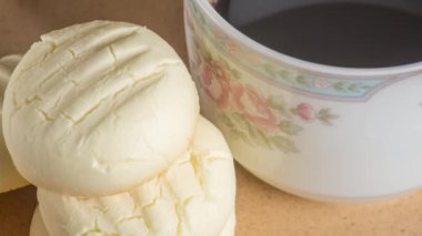 Küçük yuvarlak kurabiyeler ve kahverengi tabakta bir fincan kahve.