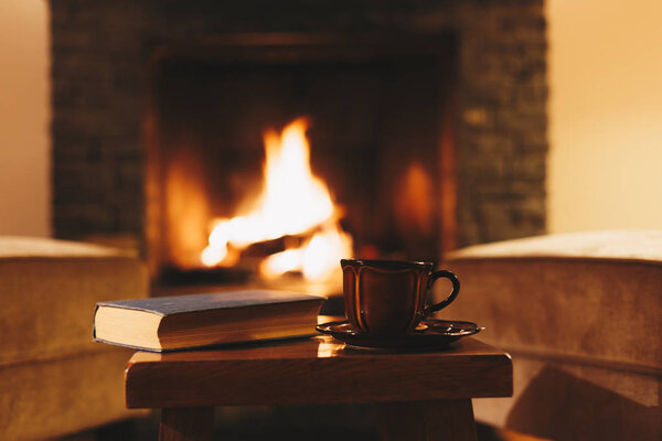 Уютный зимний вечер в горном шале. Чашка горячего напитка перед камином
