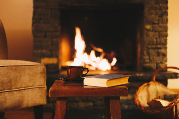 Концепция зимнего отдыха. Чашка горячего напитка перед теплым камином
